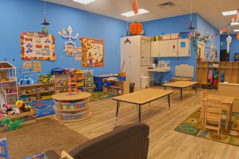 Blue classroom with toy shelves and a reading corner