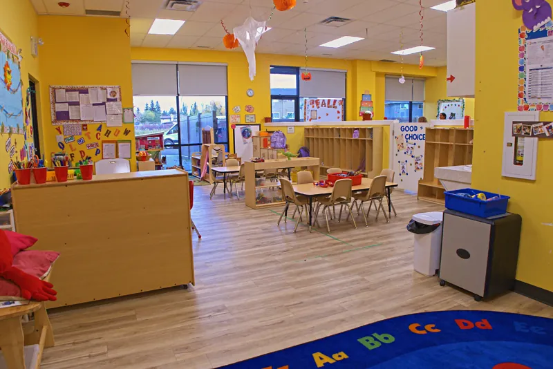 Yellow room with an alphabet rug and small tables